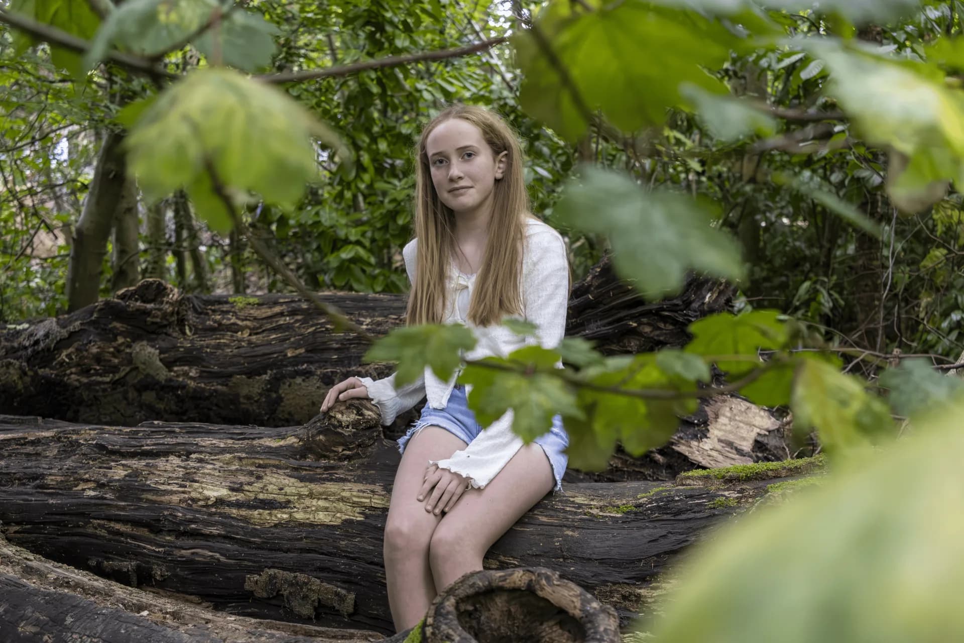 Girl sitting on a fallen tree in the woods