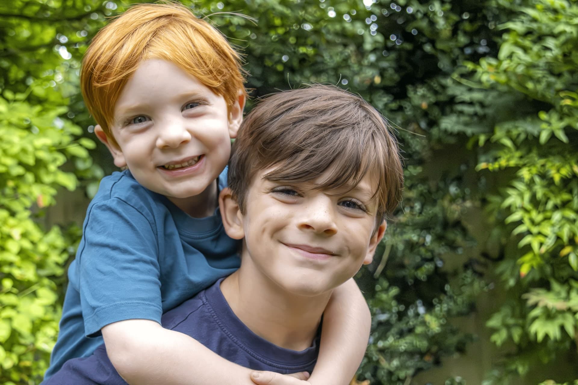 Two boys hugging and smiling in a garden