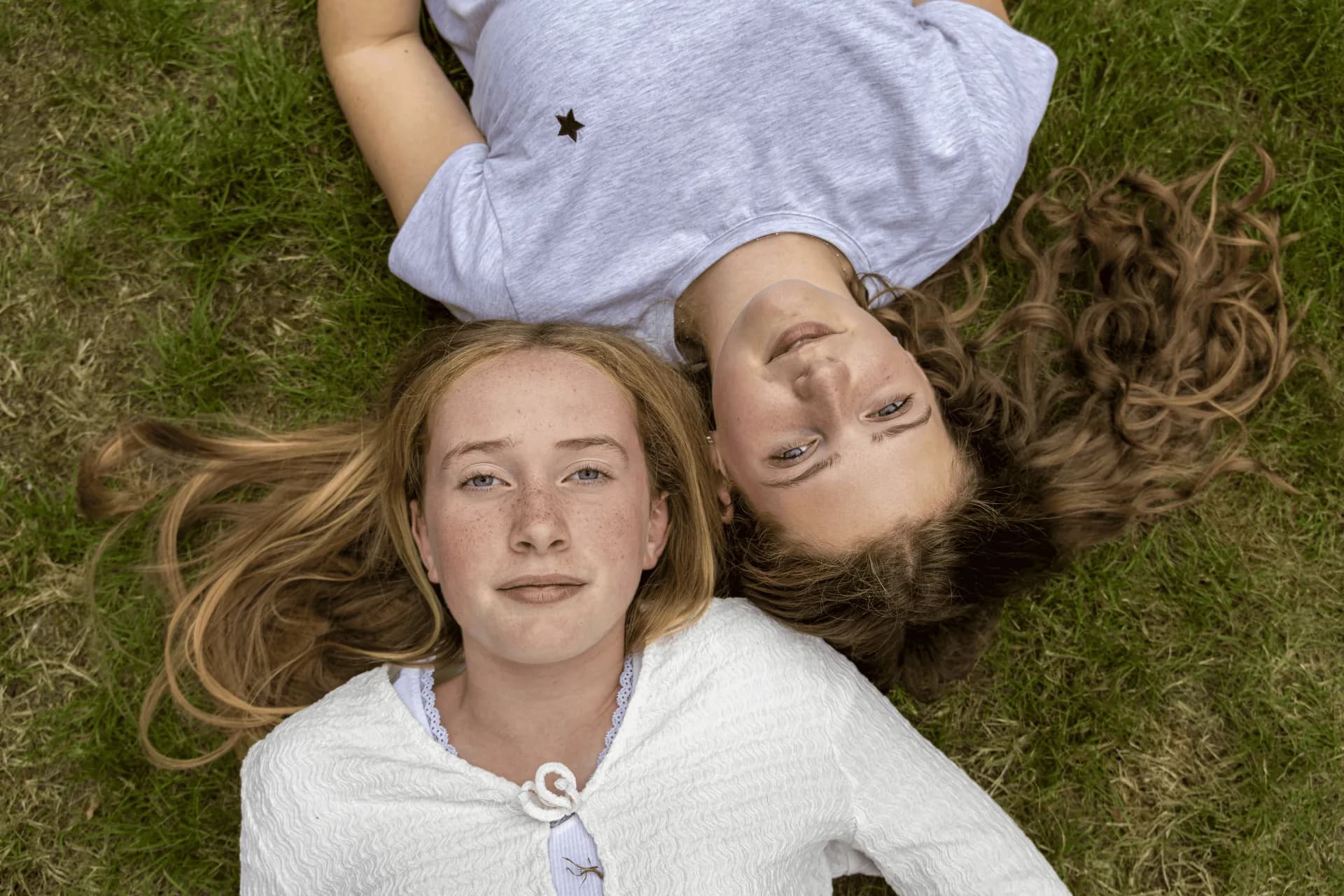 Two girls lying head to head on the grass